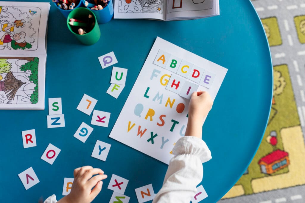 Child practicing phonics with colorful alphabet cards and worksheets during ADA Holistic Phonics session in Ahmedabad.