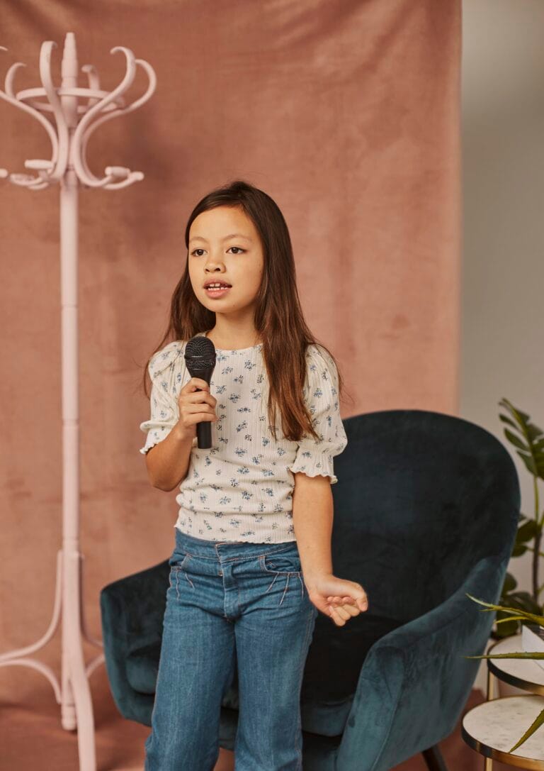 Young girl speaking into a microphone – Developing early communication skills for confidence and future success.