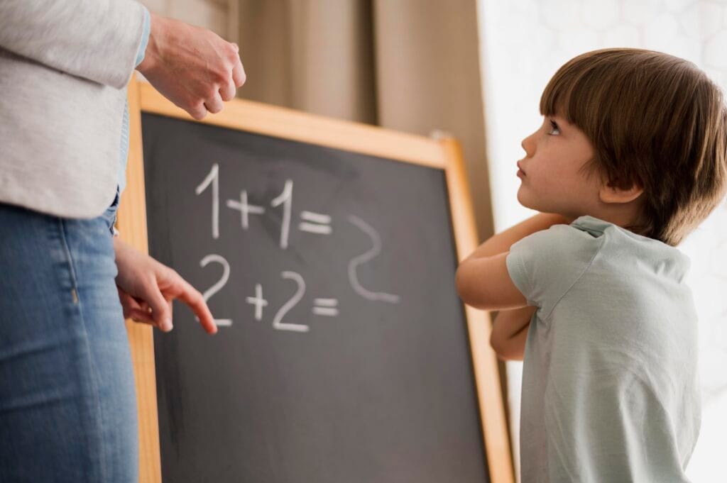 Young boy learning basic addition with teacher guidance – Beginner’s Guide to Vedic Maths for children.