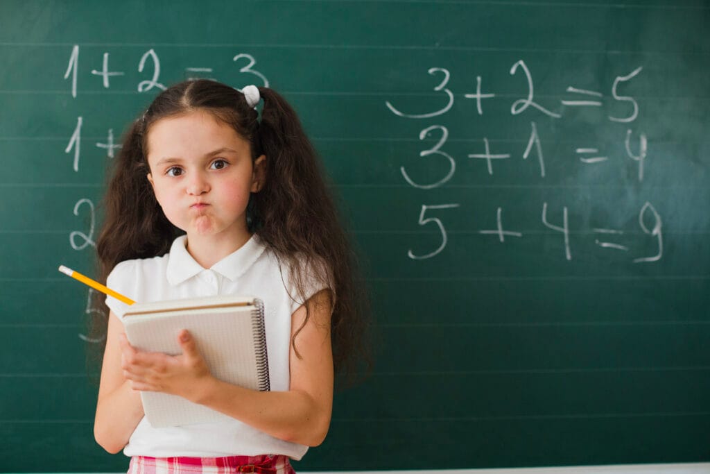Young girl learning mathematics with notebook and chalkboard – Vedic Maths tips for kids by Achievers Destination Academy.