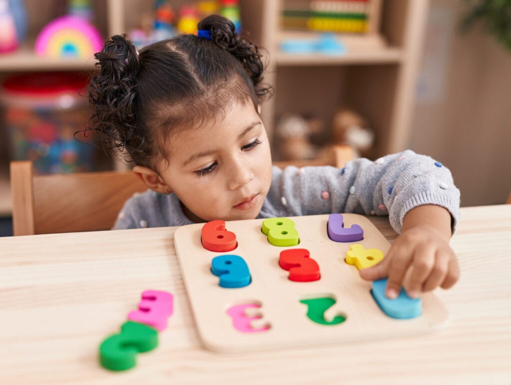 A young child solving a colorful number puzzle, showcasing learning through ADA Holistic Memory Technique classes that build 10X Confidence.