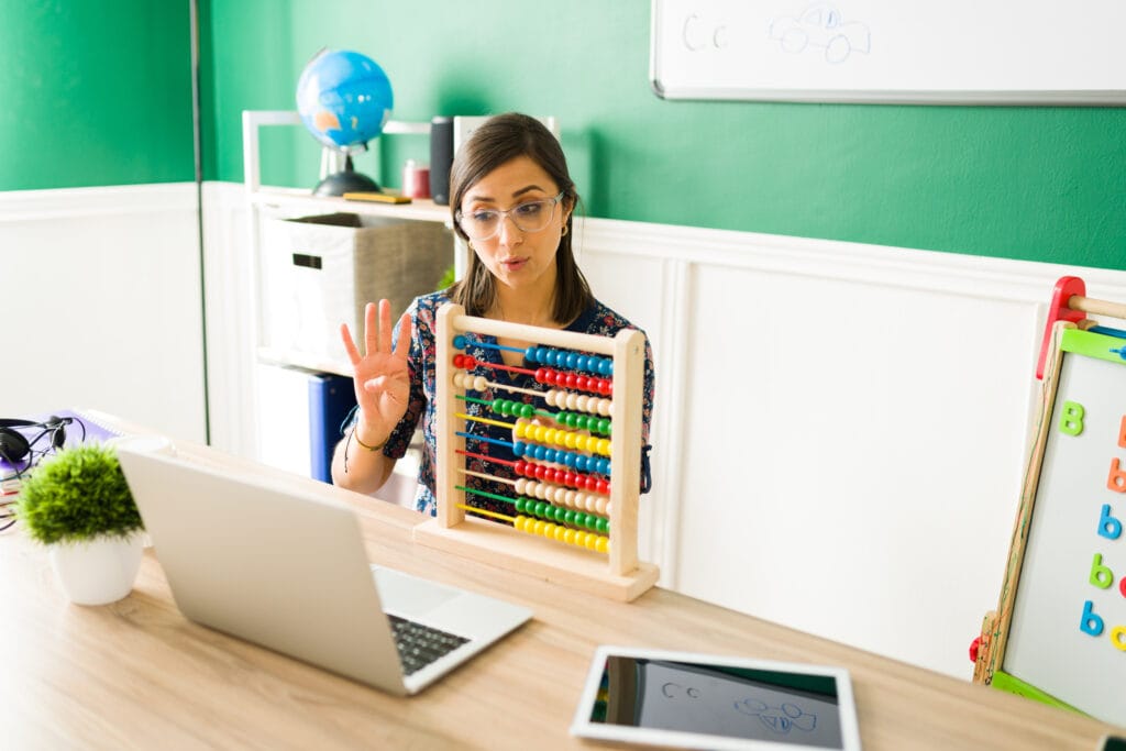 A female teacher teaching numbers with a colorful abacus during an online class for kids in Bangalore.