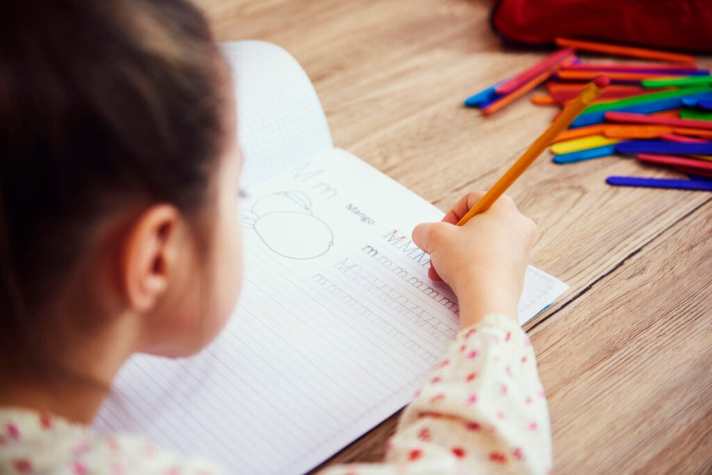 Child practicing alphabet writing in notebook – holistic handwriting improvement for kids.