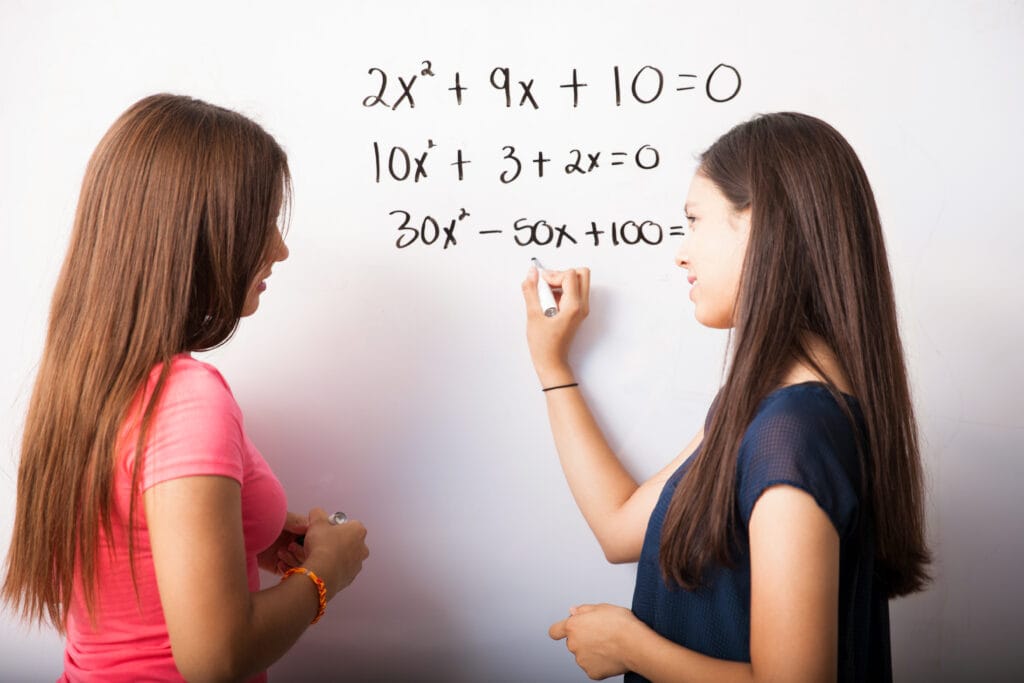 Two high school students solving algebra equations on a whiteboard with 10X Confidence at Achievers Destination Academy’s Vedic Maths classes in Kanpur.