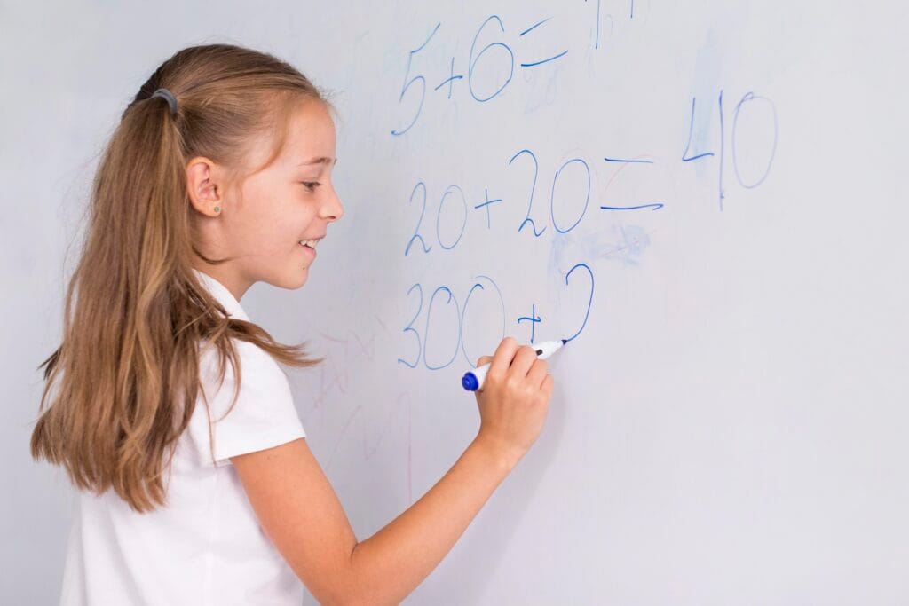 Smiling girl solving math equations on a whiteboard – benefits of Vedic Maths for students aged 10–16.