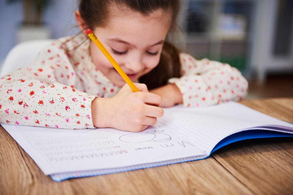 Child practicing handwriting in notebook – holistic handwriting improvement tips for kids.